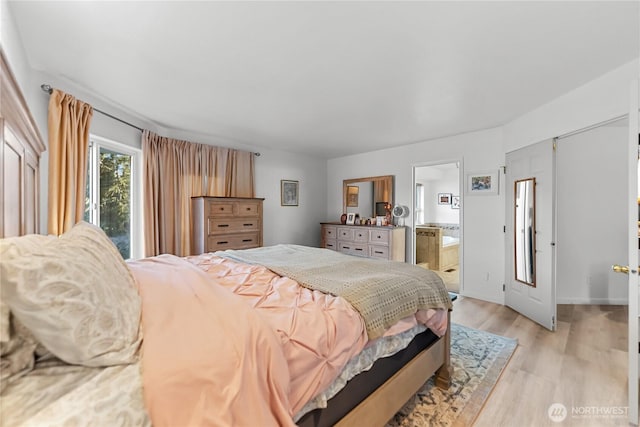 bedroom with ensuite bathroom, light wood-type flooring, and baseboards