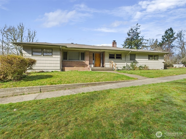 single story home with brick siding, a chimney, and a front yard