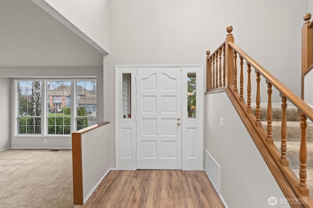 entryway featuring visible vents, baseboards, wood finished floors, and stairs