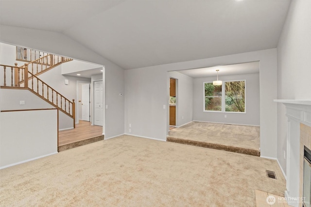 unfurnished living room featuring stairway, visible vents, carpet floors, a fireplace, and vaulted ceiling