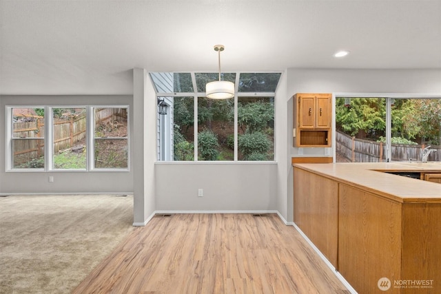 kitchen featuring baseboards, light wood-style floors, hanging light fixtures, and light countertops