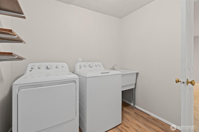 laundry room with laundry area, baseboards, light wood finished floors, and washing machine and clothes dryer