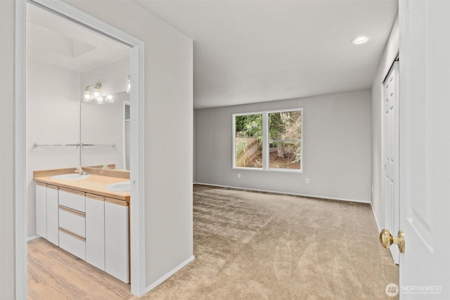 interior space featuring light colored carpet, baseboards, and ensuite bathroom