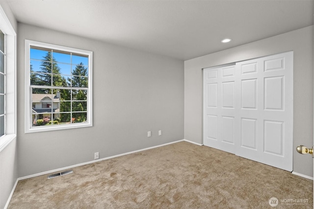 unfurnished bedroom featuring a closet, visible vents, baseboards, and carpet