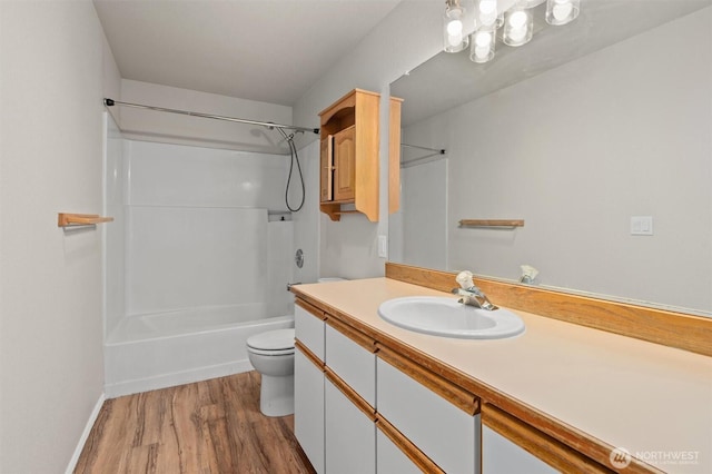 bathroom featuring toilet, shower / washtub combination, wood finished floors, baseboards, and vanity