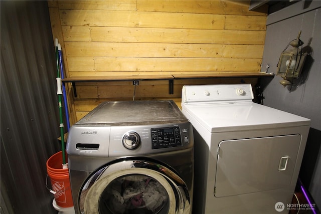 laundry area with laundry area, wooden walls, and washer and dryer