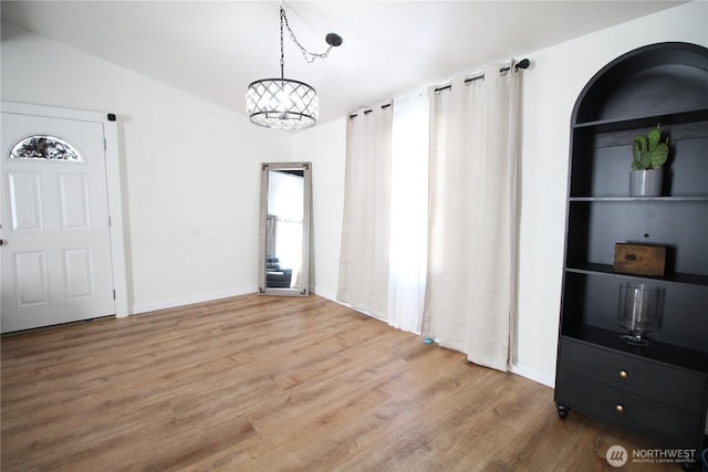 unfurnished dining area featuring built in features, a wealth of natural light, baseboards, and wood finished floors