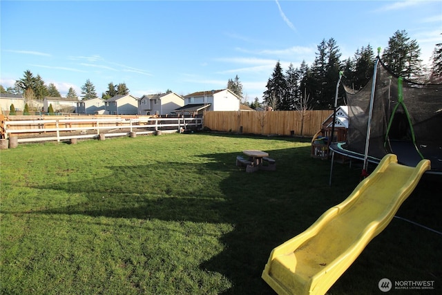 view of yard with a trampoline, a playground, and a fenced backyard