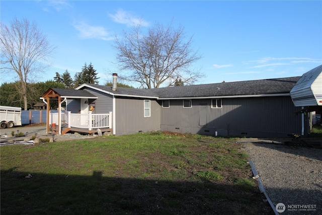 back of house featuring crawl space, roof with shingles, a deck, and a yard