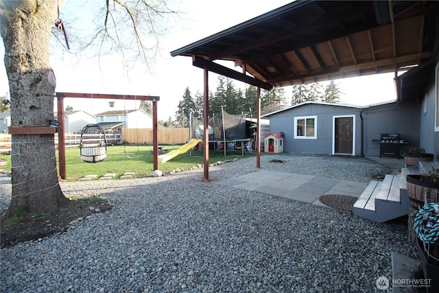 exterior space featuring a trampoline, fence, and grilling area