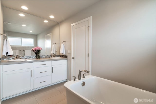 full bathroom with a sink, a soaking tub, double vanity, and tile patterned flooring