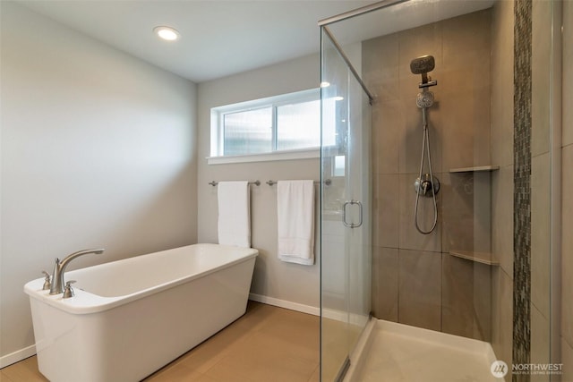 bathroom featuring a shower stall, a freestanding bath, and baseboards