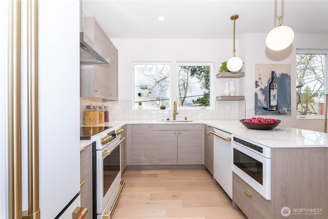 kitchen with a sink, wall chimney range hood, light wood-style floors, white appliances, and open shelves