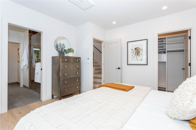 bedroom with recessed lighting, a walk in closet, visible vents, and wood finished floors