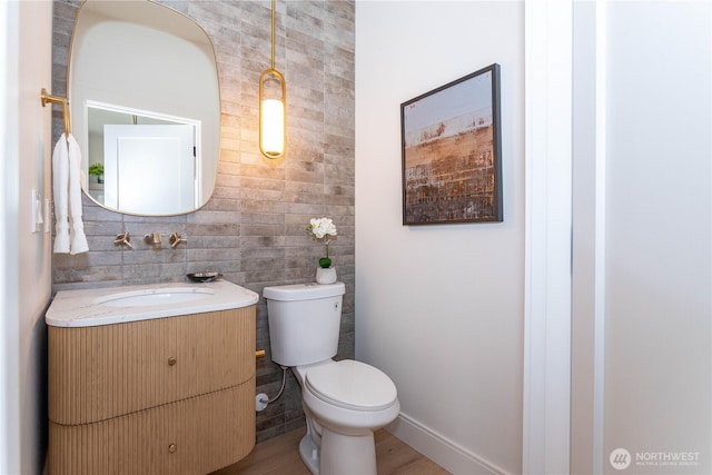 half bathroom with baseboards, toilet, and vanity