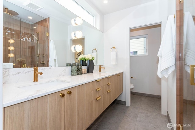 bathroom featuring a shower stall, toilet, double vanity, and a sink