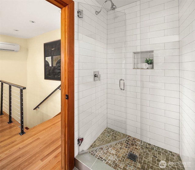 full bathroom with a wall unit AC, wood finished floors, and a stall shower