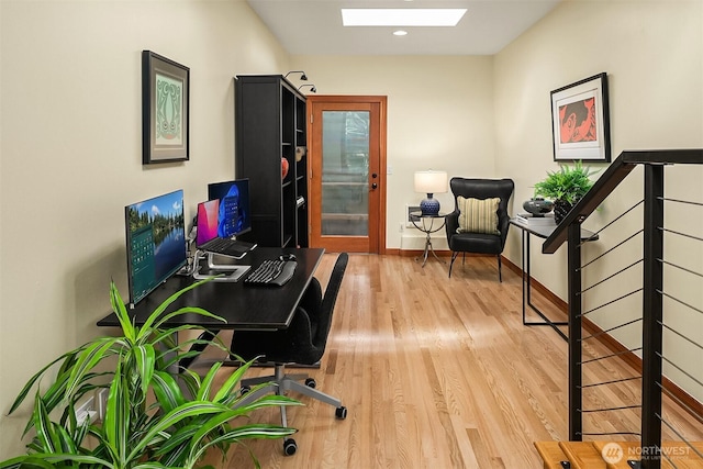 office with a skylight, baseboards, and wood finished floors