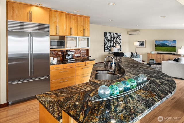 kitchen featuring a sink, stainless steel appliances, light wood-style flooring, and a wall unit AC