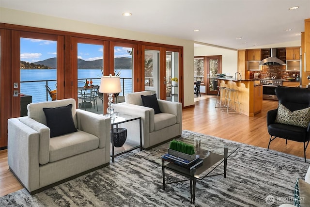 living area with recessed lighting, a water view, and light wood-style floors