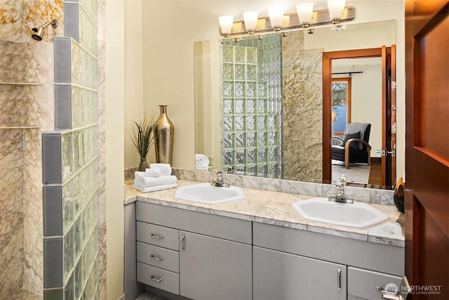 bathroom with ensuite bath, double vanity, walk in shower, and a sink