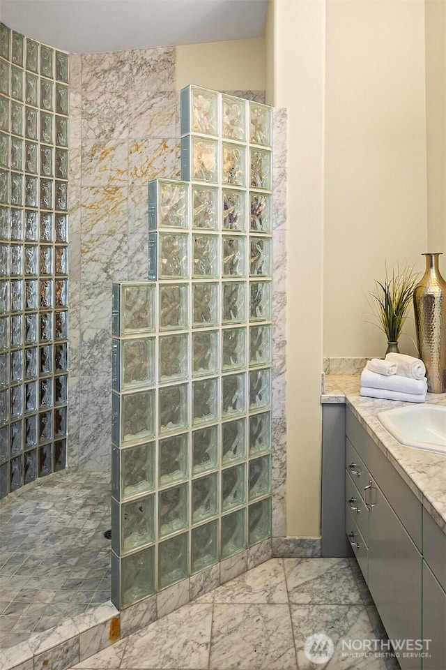 full bath featuring marble finish floor, a walk in shower, and vanity