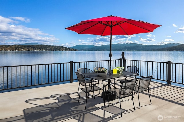 view of patio with a water and mountain view and outdoor dining space