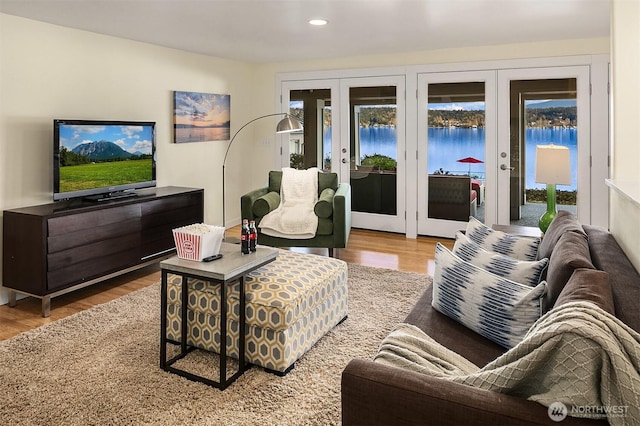 living room with recessed lighting, french doors, a water view, and wood finished floors