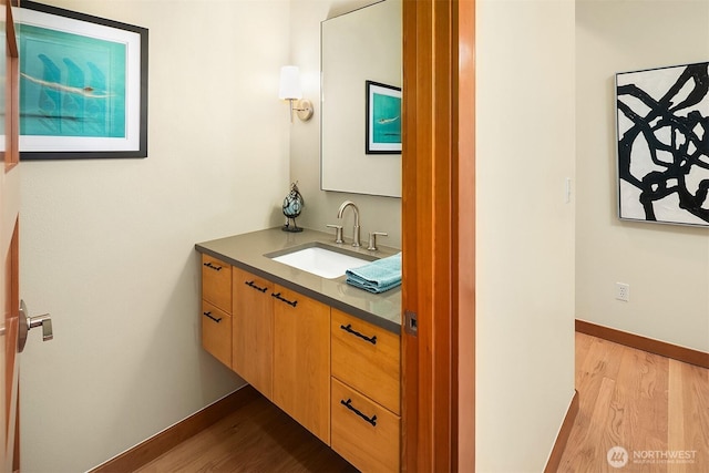 bathroom featuring vanity, wood finished floors, and baseboards