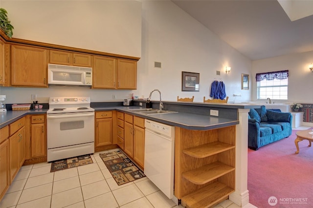 kitchen with dark countertops, open floor plan, a sink, white appliances, and a peninsula