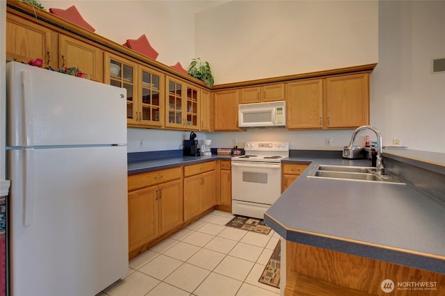 kitchen with light tile patterned floors, white appliances, a high ceiling, a sink, and dark countertops