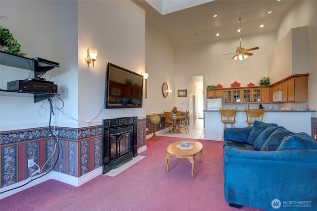 living area featuring recessed lighting, light carpet, ceiling fan, and a towering ceiling