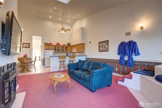 living room featuring light tile patterned floors, recessed lighting, a ceiling fan, a towering ceiling, and visible vents