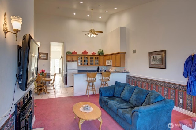 living area with a towering ceiling, light tile patterned floors, ceiling fan, and recessed lighting