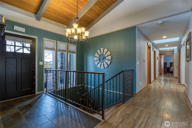 entrance foyer with baseboards, lofted ceiling with beams, wood ceiling, wood finished floors, and a chandelier