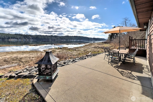 view of patio with a forest view, outdoor dining area, and a water view