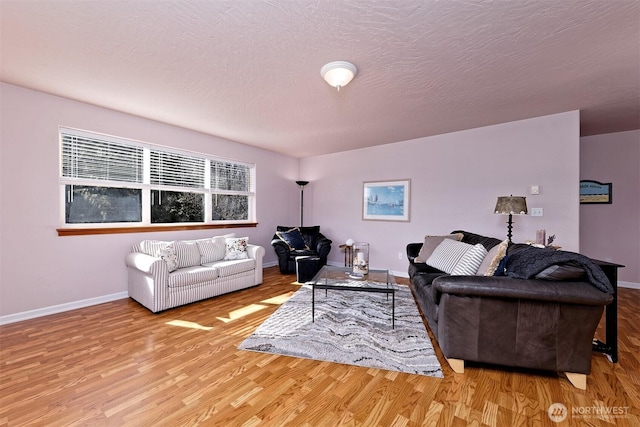 living room featuring a textured ceiling, baseboards, and wood finished floors