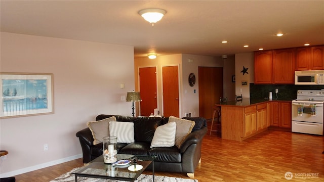 living room featuring recessed lighting, light wood-type flooring, and baseboards