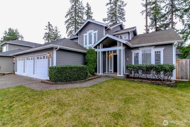 traditional-style home featuring a front lawn, aphalt driveway, fence, roof with shingles, and an attached garage