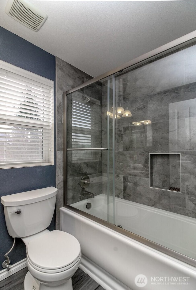 bathroom with visible vents, shower / bath combination with glass door, and toilet