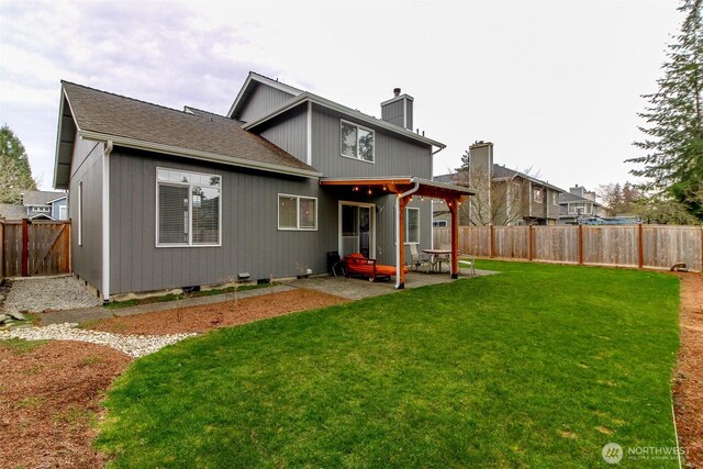 rear view of house with a patio, a lawn, a fenced backyard, and a chimney