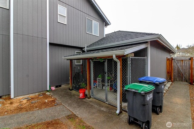 view of side of property featuring fence and a shingled roof