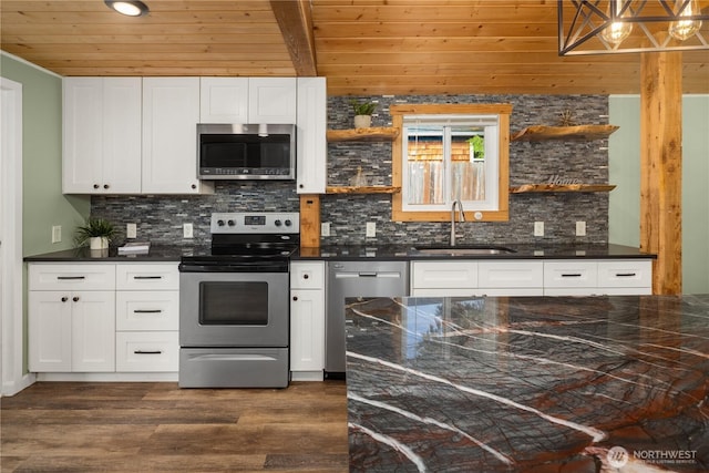 kitchen with open shelves, dark countertops, stainless steel appliances, and a sink