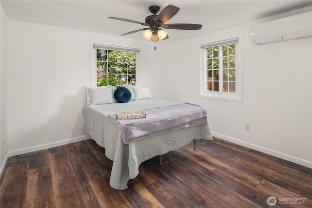 bedroom with a wall mounted AC, wood finished floors, a ceiling fan, and baseboards