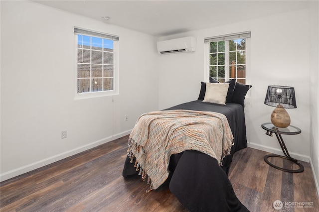 bedroom featuring an AC wall unit, baseboards, and wood finished floors