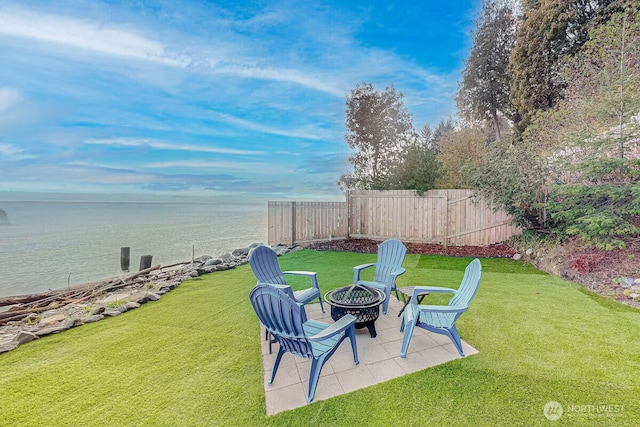 view of yard featuring a water view, an outdoor fire pit, a patio, and fence