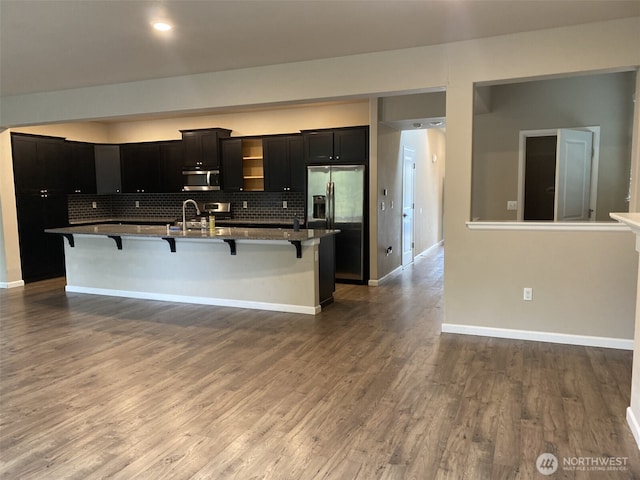 kitchen with decorative backsplash, stainless steel appliances, wood finished floors, and a kitchen breakfast bar