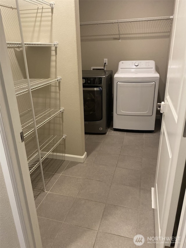 laundry room with tile patterned floors, laundry area, baseboards, and separate washer and dryer