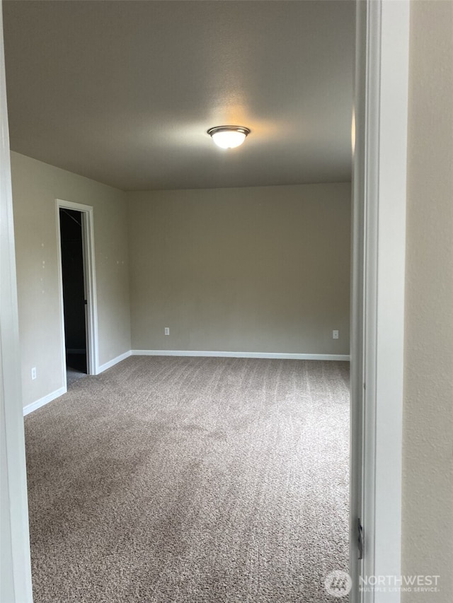 carpeted spare room featuring baseboards