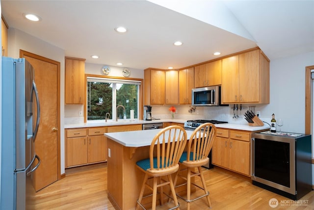 kitchen featuring light wood-style flooring, stainless steel appliances, a sink, and light countertops